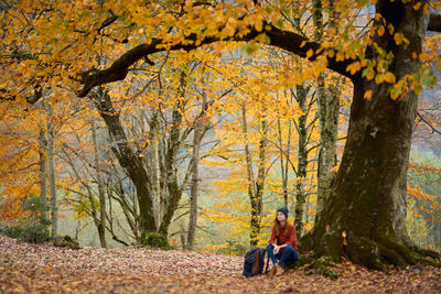 Women sitting on tree trunk during autumn