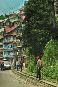 Rear view of people walking on road amidst buildings