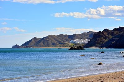 Scenic view of sea by mountains against sky