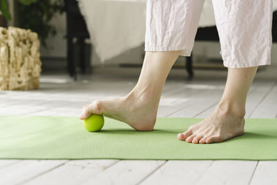 Woman stepping on ball with bare foot at home