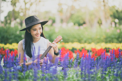 Woman playing guitar amidst blooming flowers