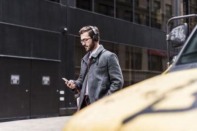 Usa, new york city, businessman with cell phone and headphones on the go