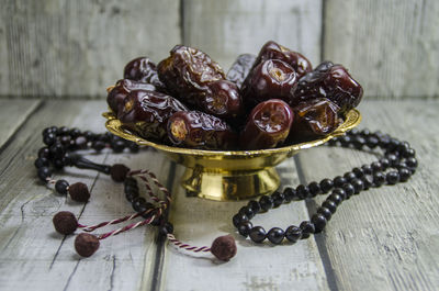 Dried date in a golden bowl on wooden background - prayer beads - concept for ramadan.