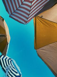 Low angle view of parasol against clear blue sky