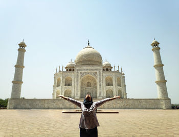 Woman with arms outstretched standing against taj mahal