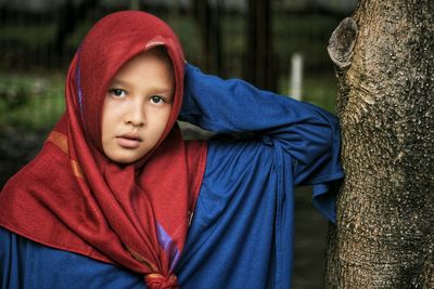 Portrait of girl by tree trunk