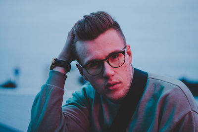 Close portrait of young man wearing eyeglasses sitting outdoors