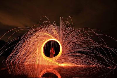 Man spinning wire wool at night