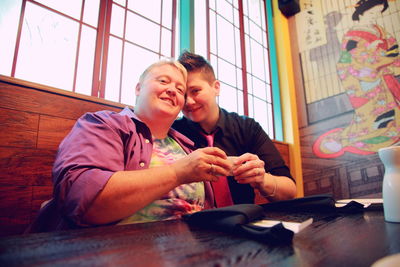 Portrait of lesbian couple holding coffee cups at restaurant