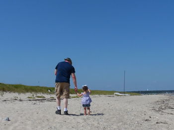 Full length of boys on beach against clear sky