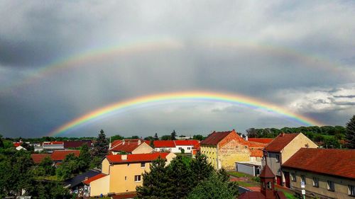 Rainbow over houses against sky