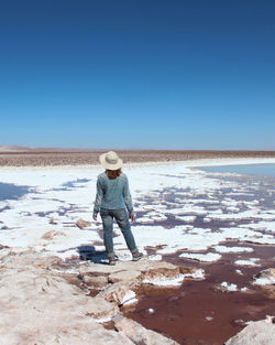 Full length of man standing on beach against clear blue sky