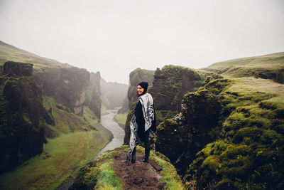 Young man on cliff against mountains