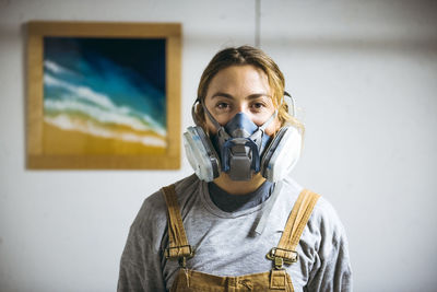 Portrait of female resin artist in homemade art studio with respirator