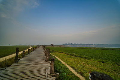 Footpath amidst field against sky