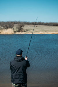 Rear view of man fishing in water