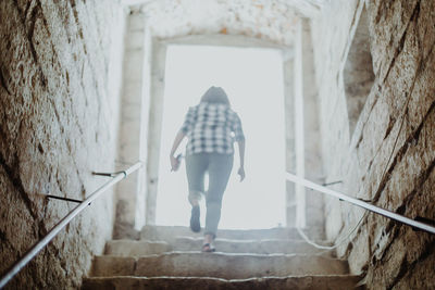 Rear view of woman standing on staircase