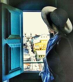 Rear view of man standing against window