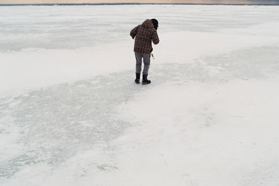 Full length rear view of man walking on snow