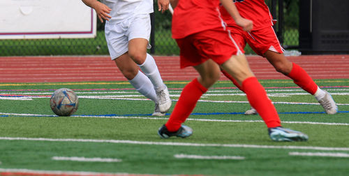 Three high school boys fighting for the soccer ball during a match.