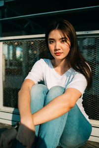 Portrait of a beautiful young woman sitting on railing