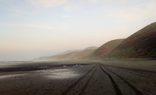 Scenic view of road by beach against sky