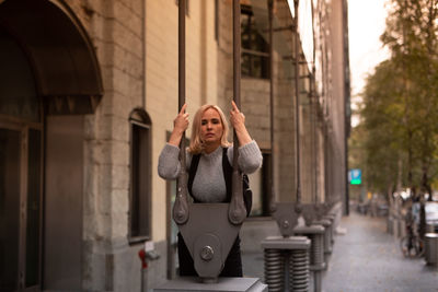 Portrait of woman standing by metallic equipment in city