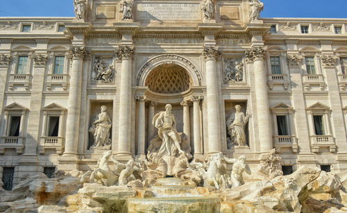 Low angle view of statues and historic building at trevi fountain