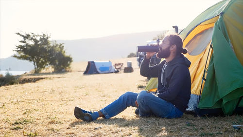 Rear view of man photographing on field