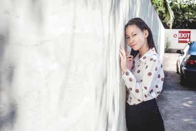 Beautiful young woman standing on wall in city