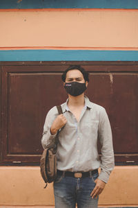 Young man wearing sunglasses standing against wall