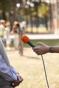 Close-up of hand holding microphone against man