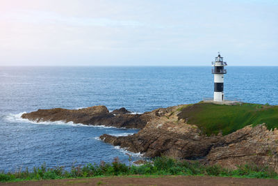 Lighthouse by sea against sky