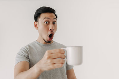 Portrait of mid adult man holding drinking glass against white background