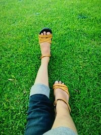 Low section of woman wearing sandal on grassy field