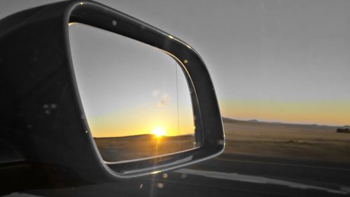 Close-up of side-view mirror against sky