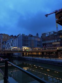 Bridge over canal by buildings against sky