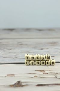 Close-up of text on table at beach against sky