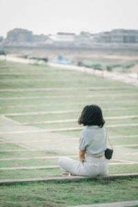 Rear view of woman sitting on land