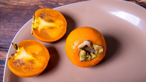 Persimmon cut into halves on a plate on a wooden table,copy space,closeup