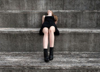 Full length of woman sitting against wall