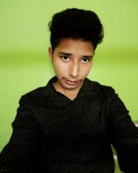 Portrait of young man standing against gray background
