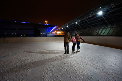 Rear view of people ice-skating at night