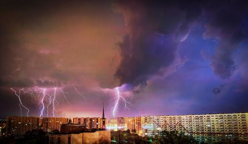 Lightning over illuminated buildings in city at night