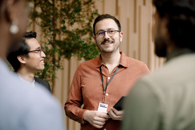 Smiling male entrepreneur discussing with delegates in seminar at convention center