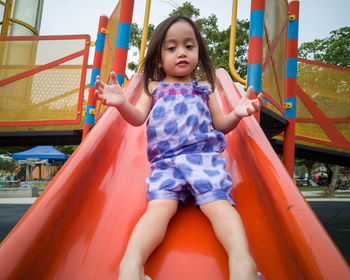 Toddler girl playing on a slide at a playground