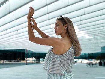 Young woman with arms raised standing in city