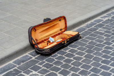 Open violin case lies on old cobblestone in city. street musician collects money