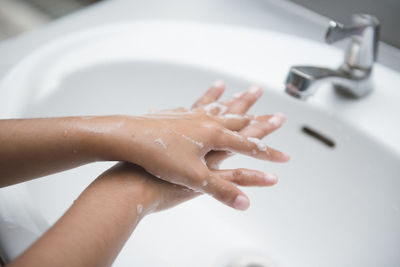 Cropped image of woman washing hands in sink at home