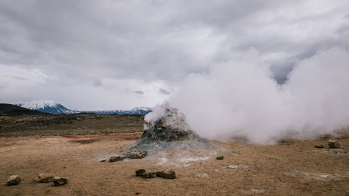 Steam emitting from volcano against cloudy sky